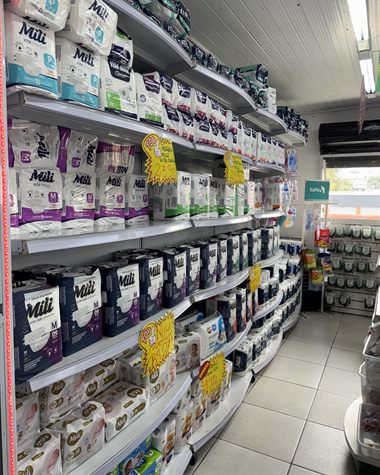Corredor com prateleiras cheias de fraldas geriátricas e infantis de vários tamanhos.