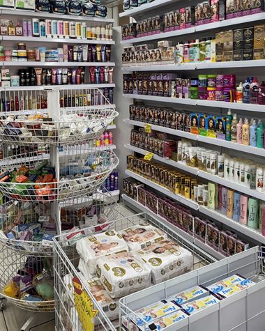 Prateleiras de perfumaria e produtos para cabelo, com um expositor giratório no meio do corredor.